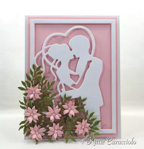 You can create an elegant framed wedding card using die cut paper flowers.