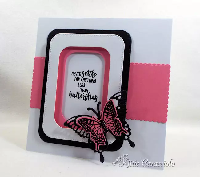 A pink and black die cut butterfly is pretty on a clean and simple background.