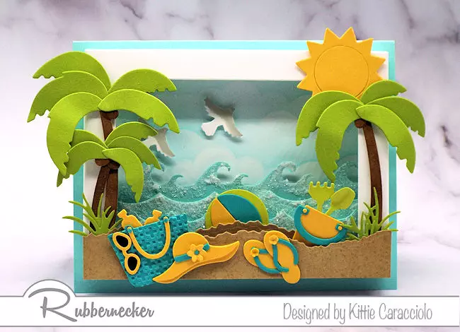This shadow box frame beach scene is so inviting with the colorful beach accessoires and sparkling ocean waves.