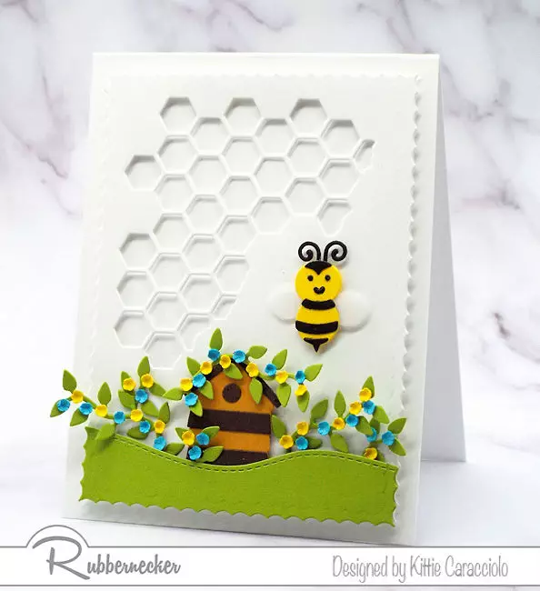 A paper pieced handmade greeting card featuring a bumblee and a die cut honeycomb background.