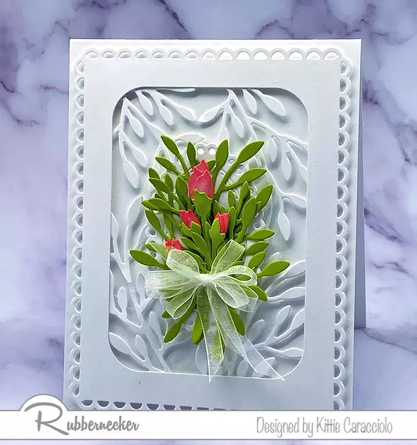 my white on white handmade floral card idea with a foliage-laden background and a bright pop of color with rosebuds and greenery all made using dies from Rubbernecker