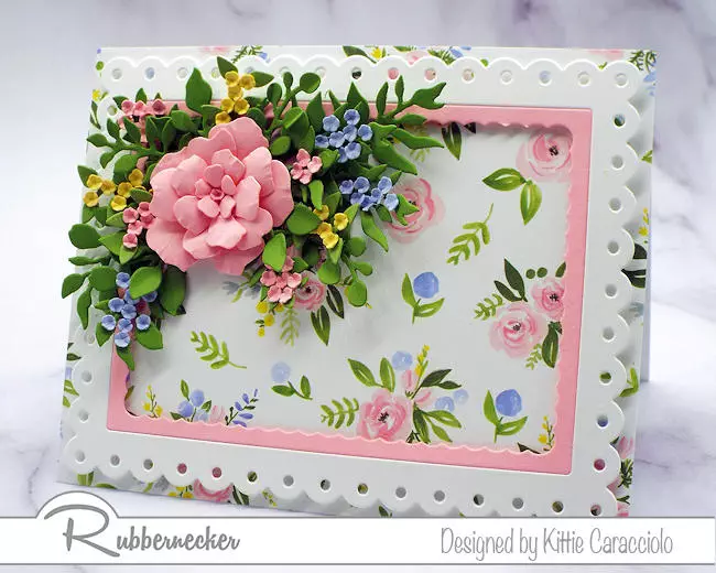 a handmade flower bouquet card with a lush bunch of realistic paper flowers mounted on a die cut frame over patterned paper