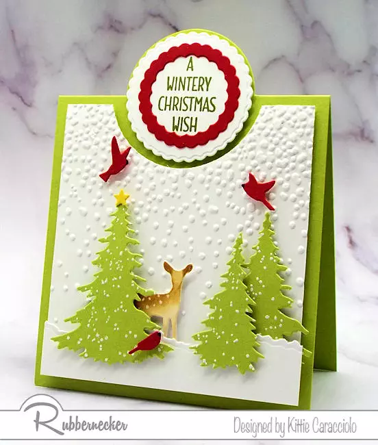A sweet and serene Christmas bib overlay card with a darling fawn in a charming snowscape all made with dies from Rubbernecker and a premade card base from The Paper Cut.