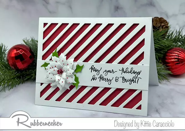 A handmade die cut poinsettia Christmas card with a 3D flower over a graphic background.