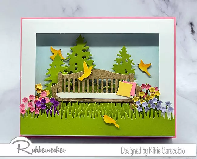 A summer scene greeting card idea made with dies from Rubbernecker to create the beautiful bench surrounded by flora and fauna.