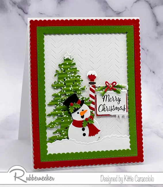 With a snowy ground, winter tree, textured background and an iconic winter sign post, this handmade die cut snowman card created using dies from Rubbernecker checks all the festive Christmas boxes.