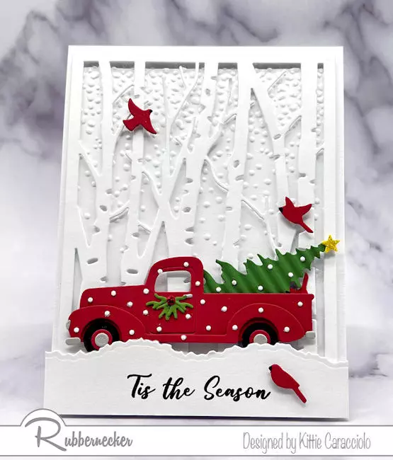 A wintry scene card handmade with die cuts for the birch trees, the classic red pickup and all the charming details added to this beautiful card.